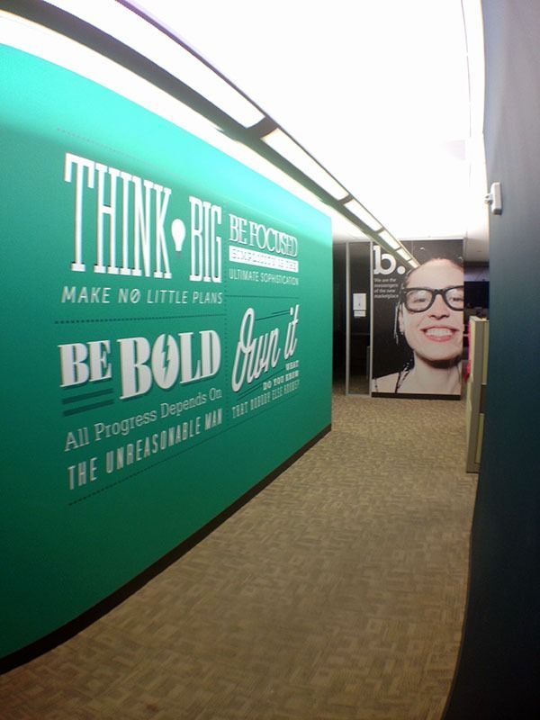 Hallway with a green motivational mural and a large portrait poster at the end