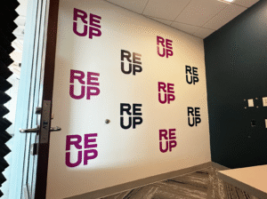 Wall with repeating “REUP” logos in black and purple inside a hallway