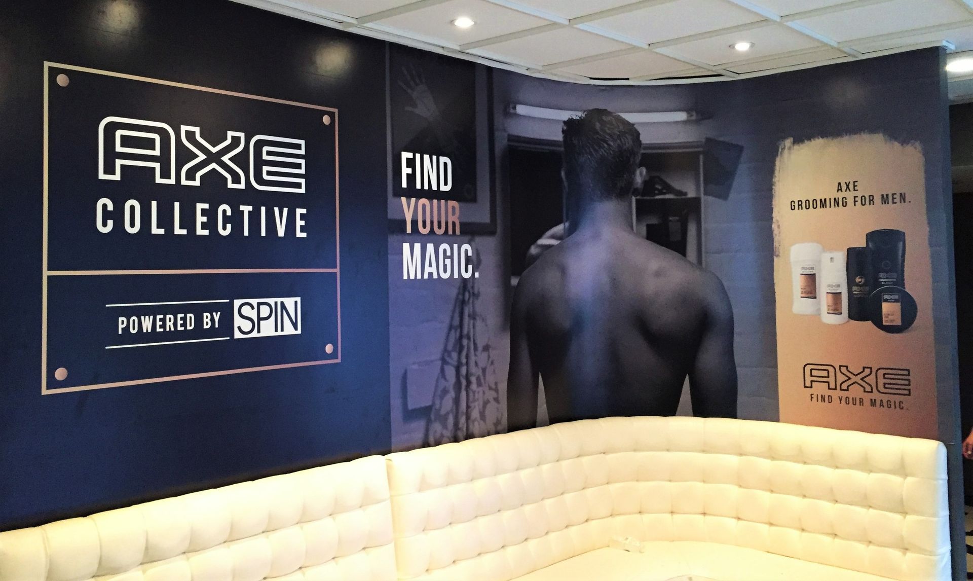 AXE Collective promo wall with “Find your magic” sign and a person seen from behind in a store display
