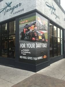 Corner of a lounge with a Red Bull promo poster and “FOR YOUR DAILY RAGE” text on the wall.