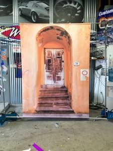 Poster of a peach-colored arched doorway and stairs displayed in a garage or workshop.