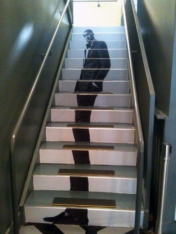 Shadowy figure on a stairwell, with a black cat at the bottom step