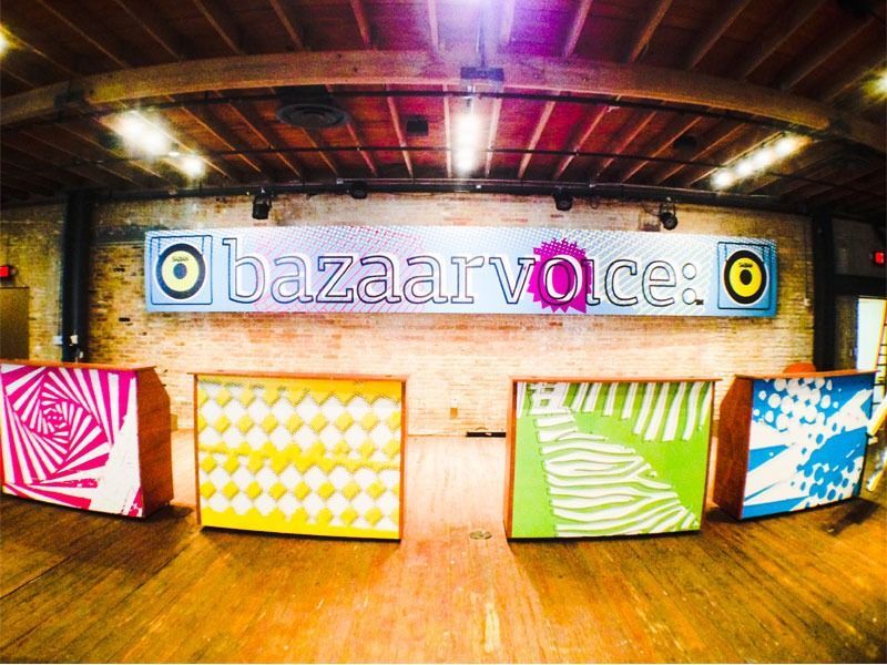 Colorful bazaarvoice booth with patterned panels in a brick-walled, wood-floored indoor venue