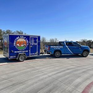 Blue pickup towing a blue enclosed trailer on a sunny paved lot