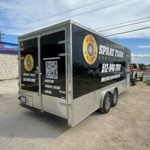 Black enclosed trailer with “Spray Foam Specialties” branding parked on a lot.