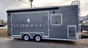 Gray ALIENWARE trailer with two wheels parked outdoors on a street