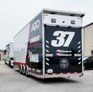 Black race trailer with large white number 37 parked on a road.