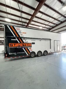 White St Peter trailer with black and orange graphics parked inside a large warehouse