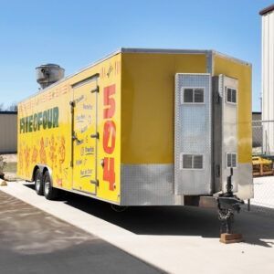 Yellow food trailer with large red “504” parked outdoors on a sunny street.