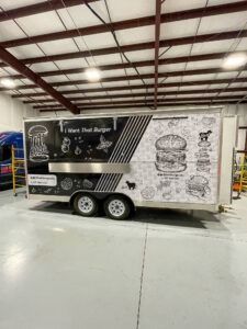 Black and white trailer with food truck graphics parked inside a warehouse