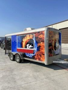 Trailer with colorful flame-and-skull graphics parked on a sunny concrete lot