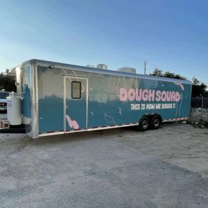Trailer with Dough Sourd signage parked on a gravel lot at sunset