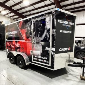 Black and red Williamson County Equipment trailer with CASE IH logo parked indoors at a trade show