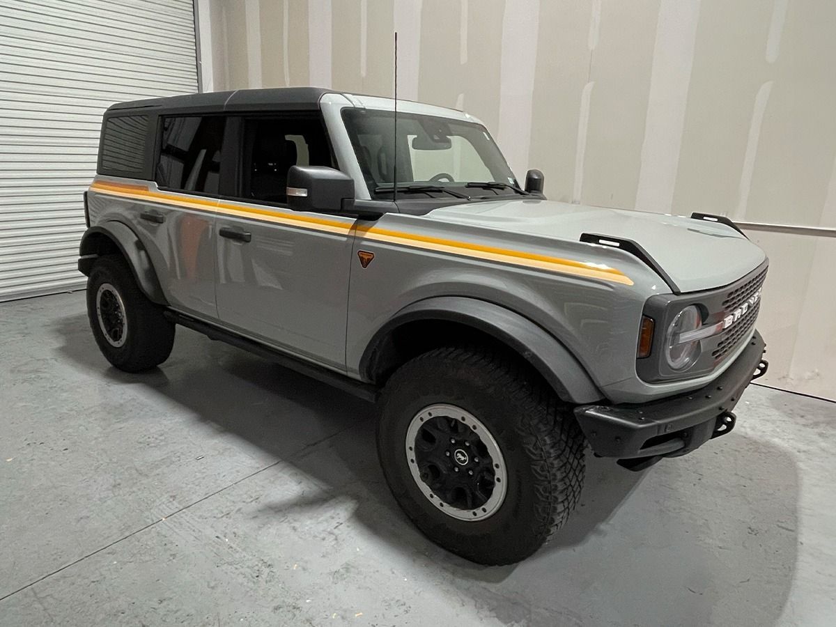 Gray off-road SUV with yellow stripe parked indoors in a studio-like garage