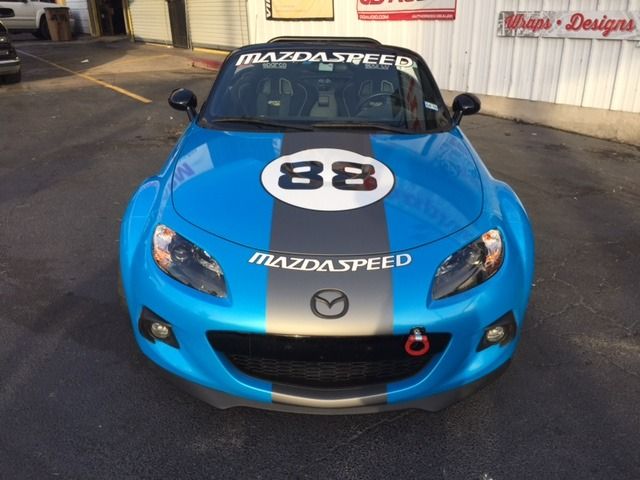Blue Mazda race car with number 88 on the hood, parked in a garage.