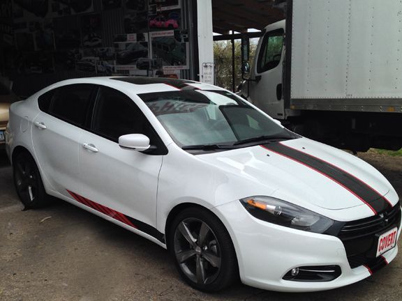 White sedan with black-and-red racing stripes parked in a garage or service bay