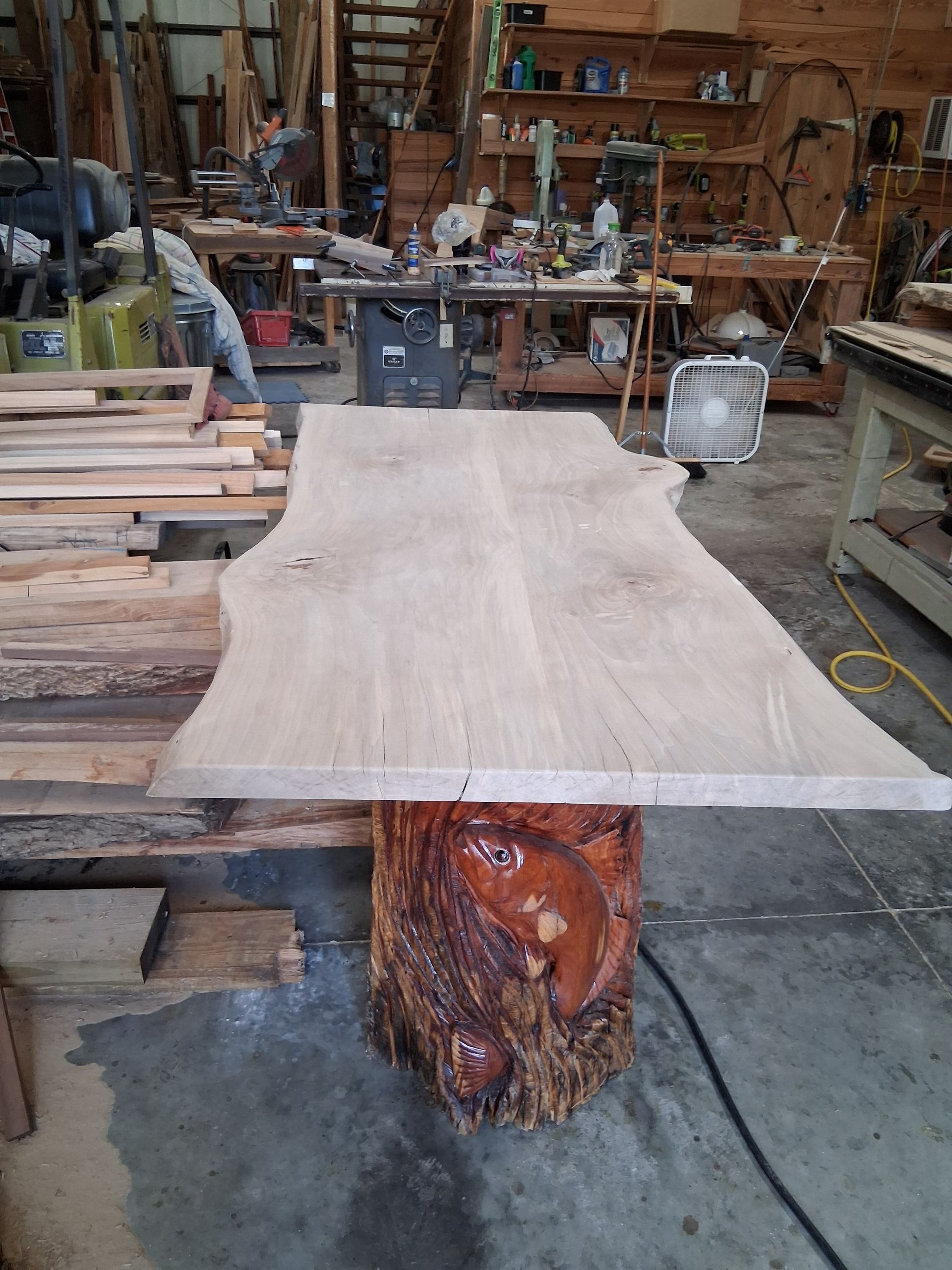 Wood slab on a rustic workshop table, with tools and lumber in the background.
