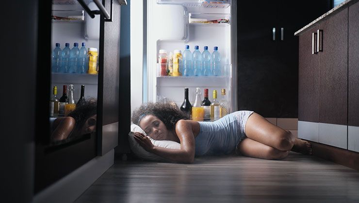 woman sleeping in front of her refrigerator since it was too hot