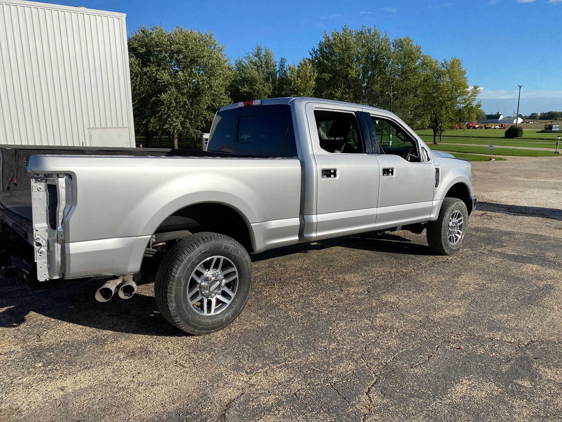 a silver pickup truck is parked in a gravel lot