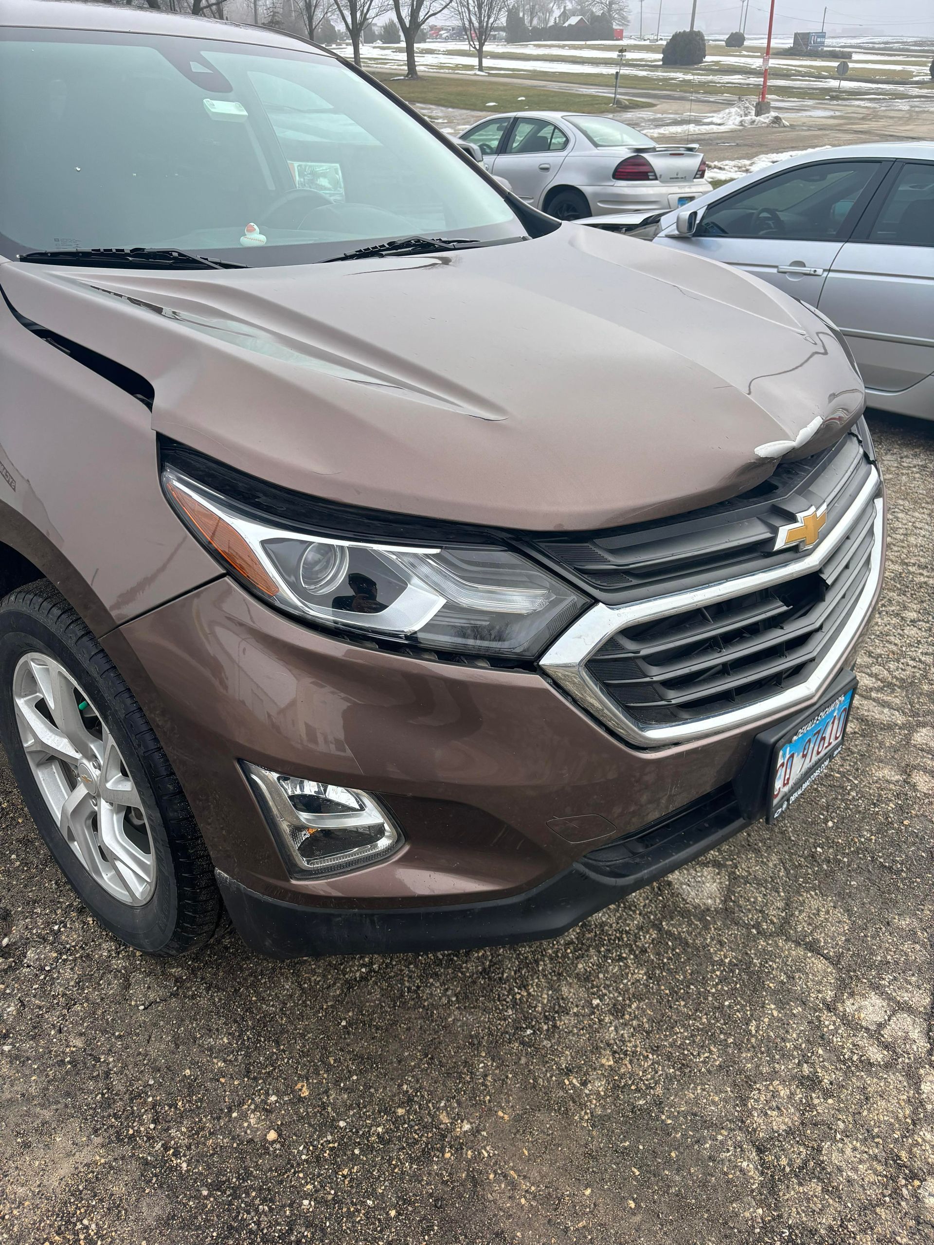 a brown chevrolet equinox is parked in a gravel lot