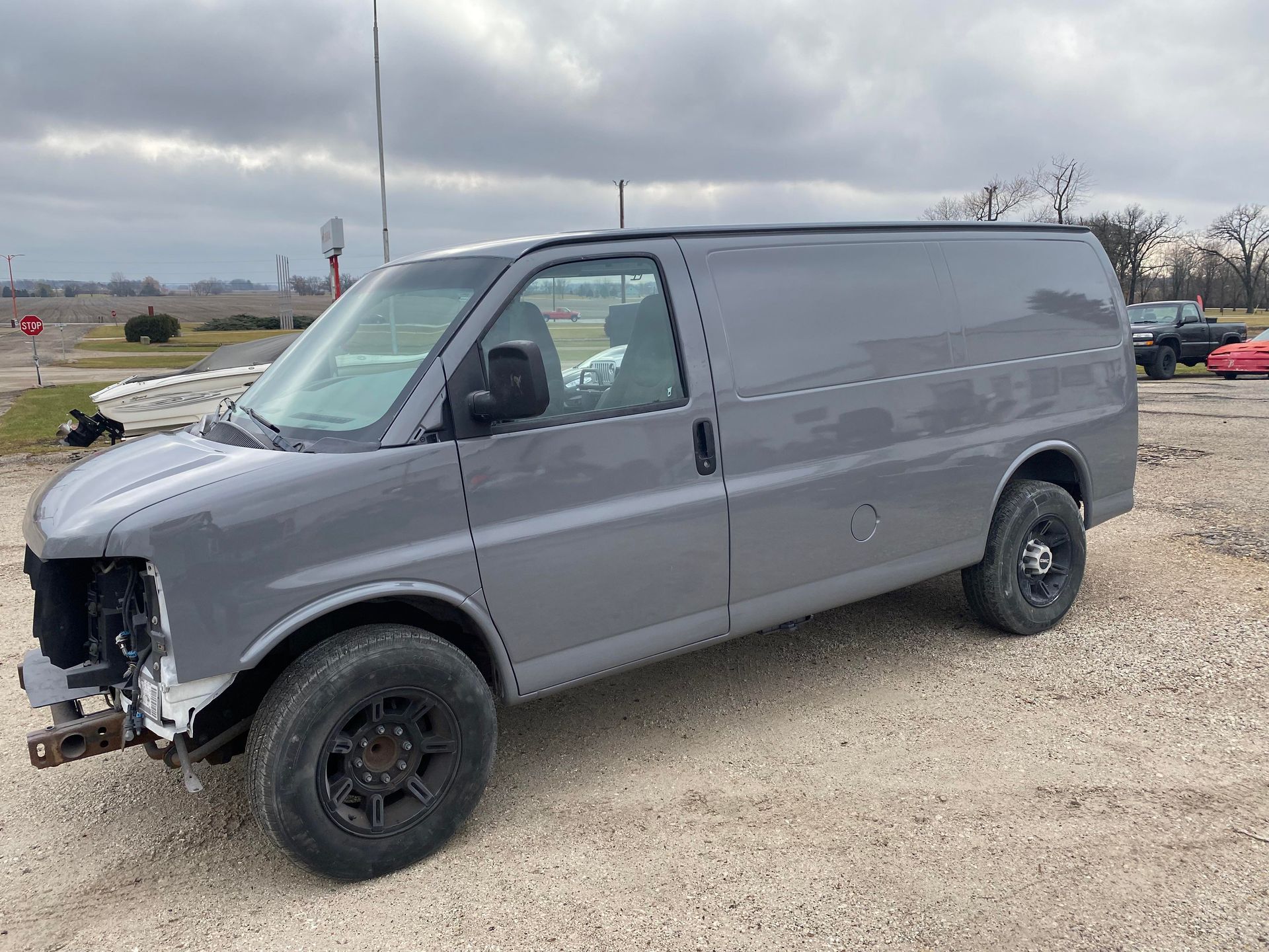 a gray van is parked in a gravel lot