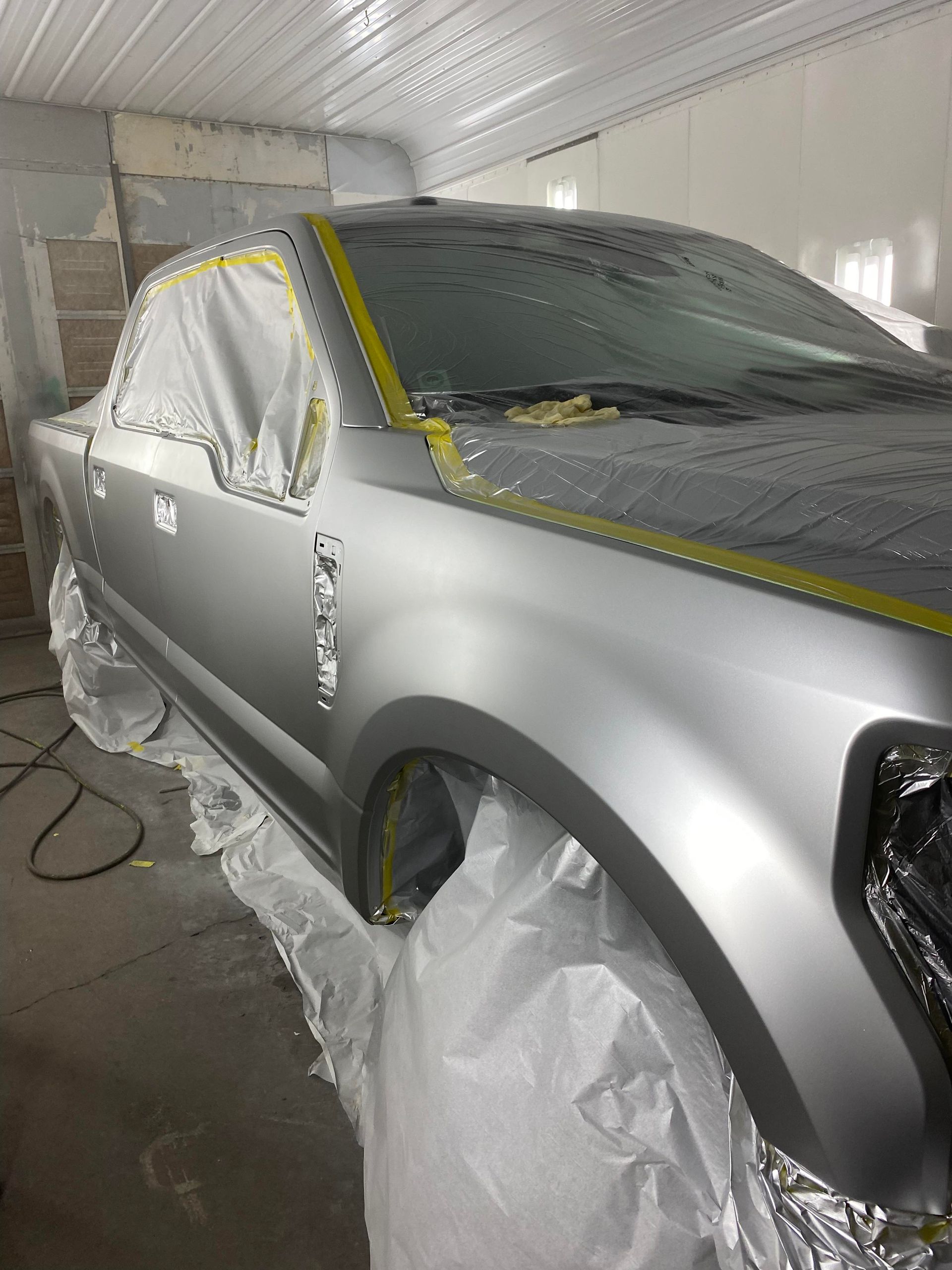 a silver car is being painted in a garage