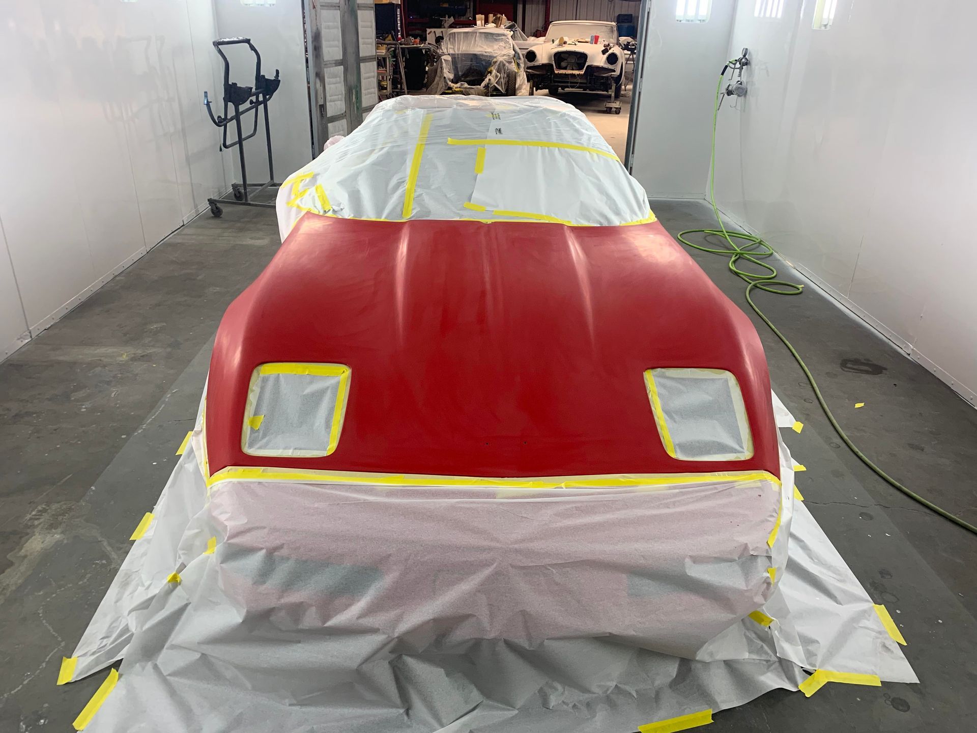 a red car is being painted in a paint booth