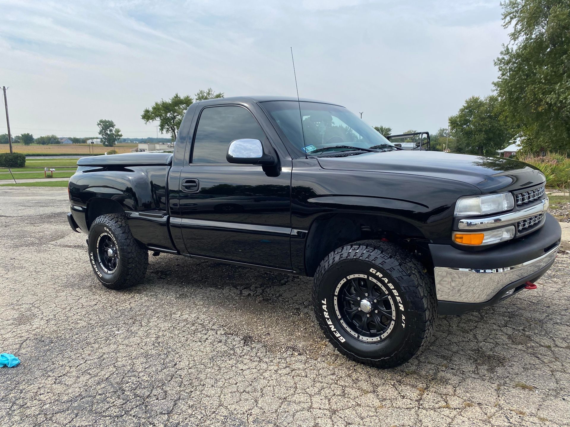a black truck is parked on a gravel road