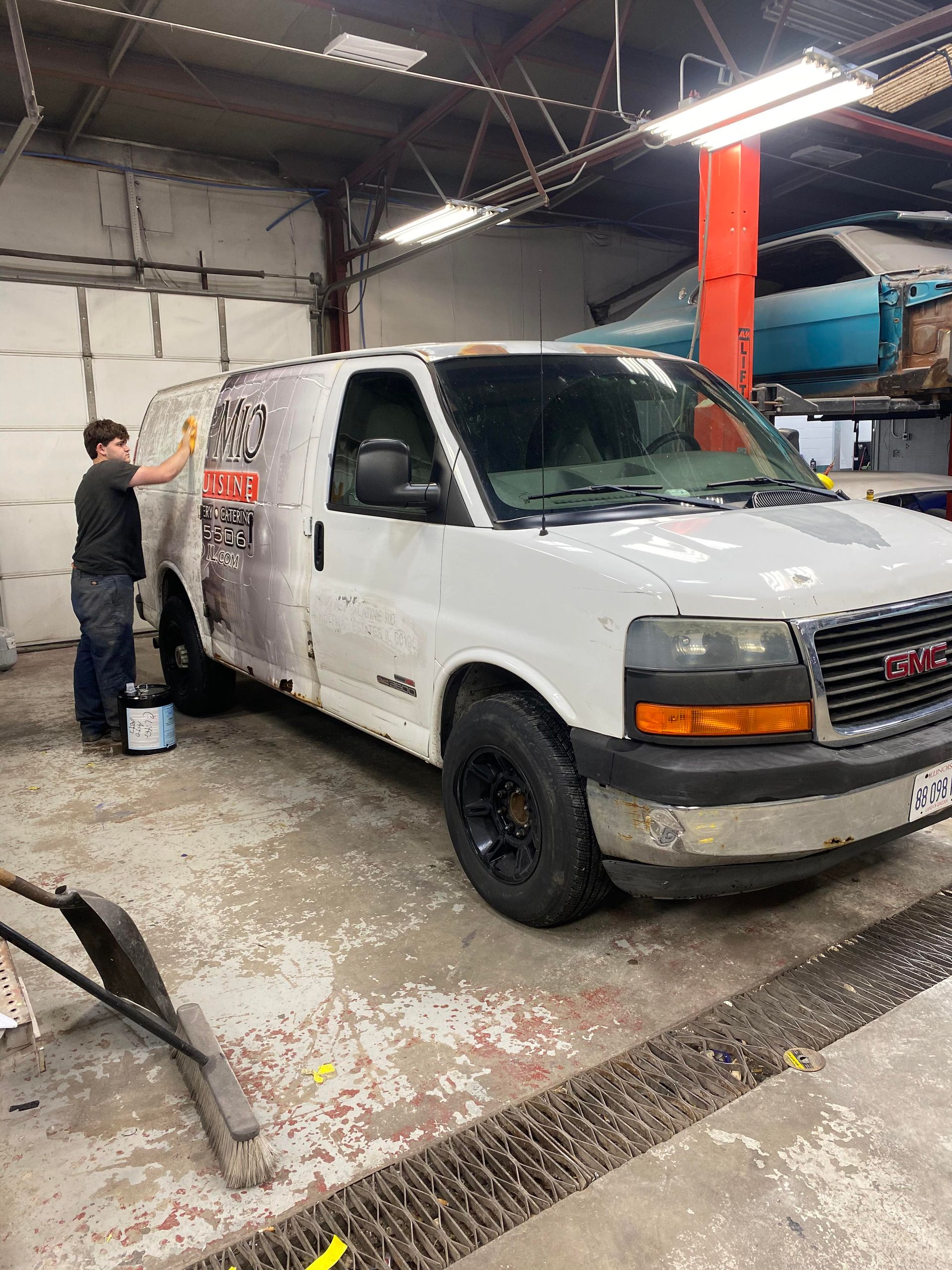 a man is painting a white van in a garage