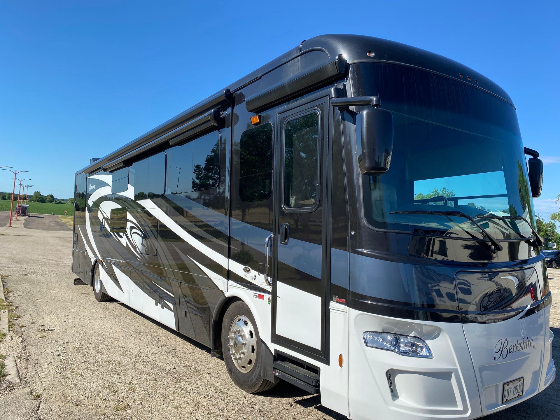 a large black and white rv is parked in a gravel lot