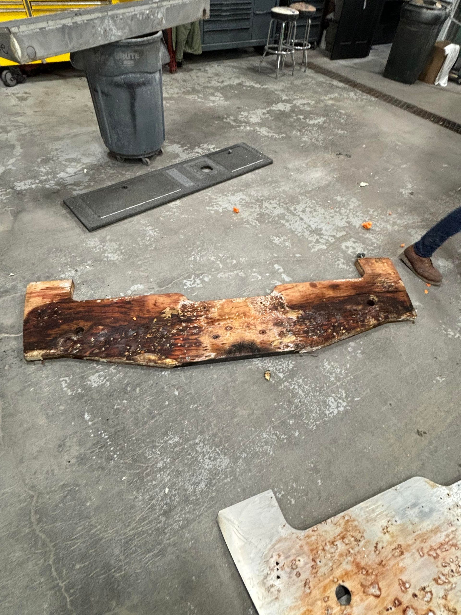 a piece of wood is laying on the ground next to a trash can