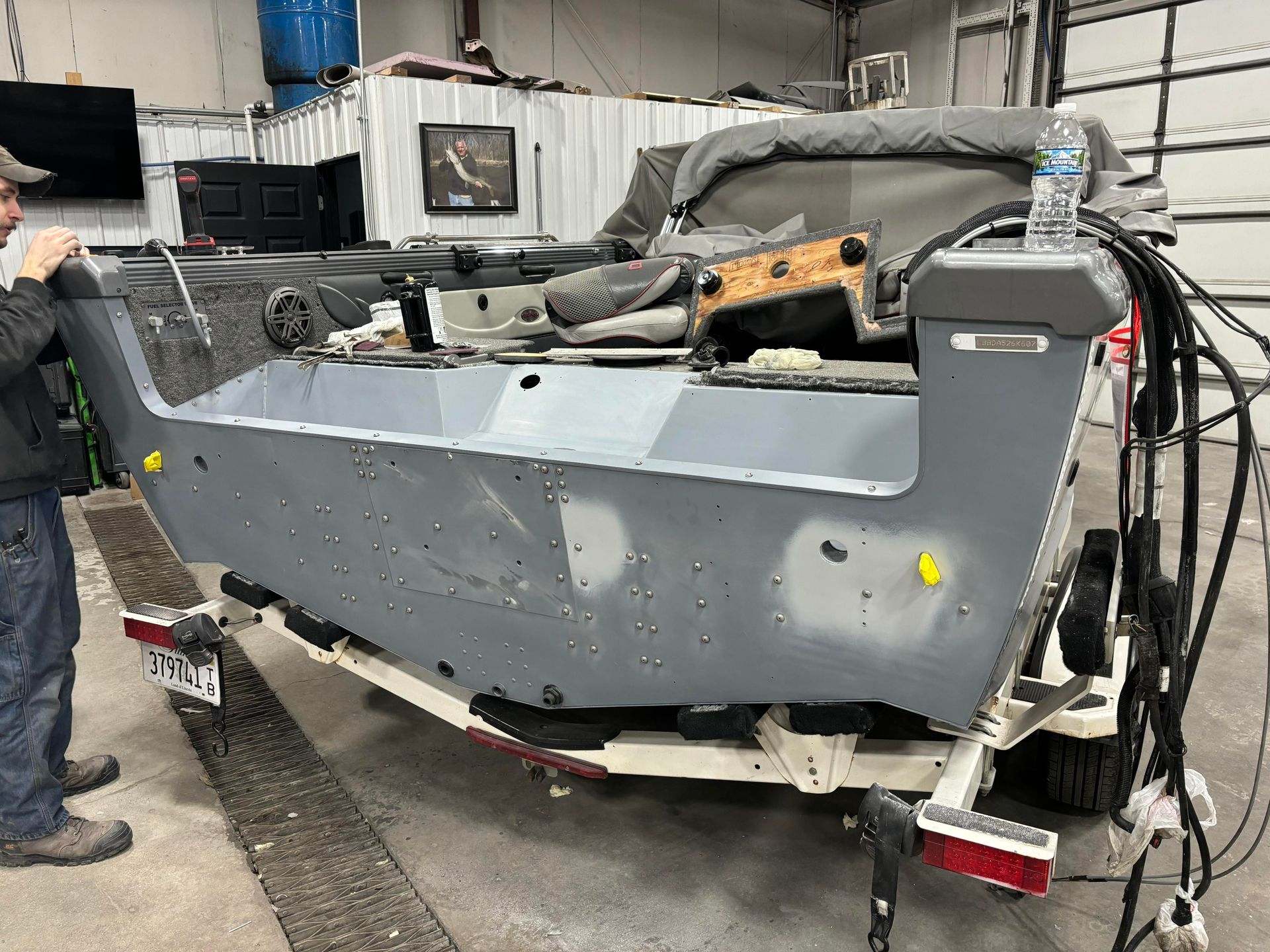 a man is standing next to a boat on a trailer in a garage