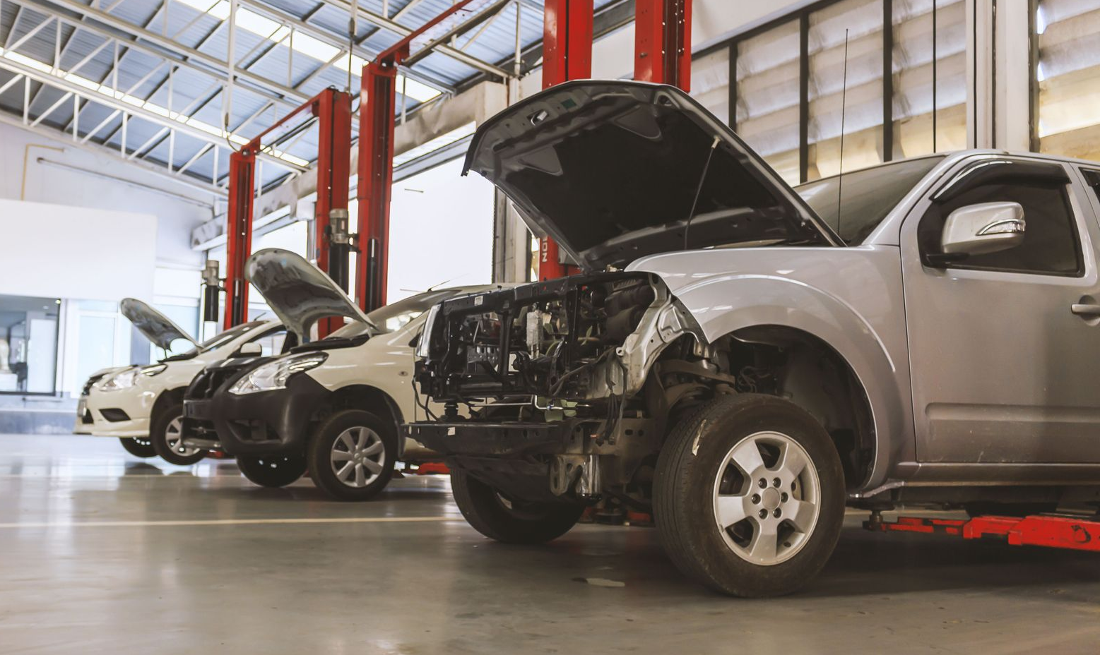 Cars with open hoods in an auto repair shop.