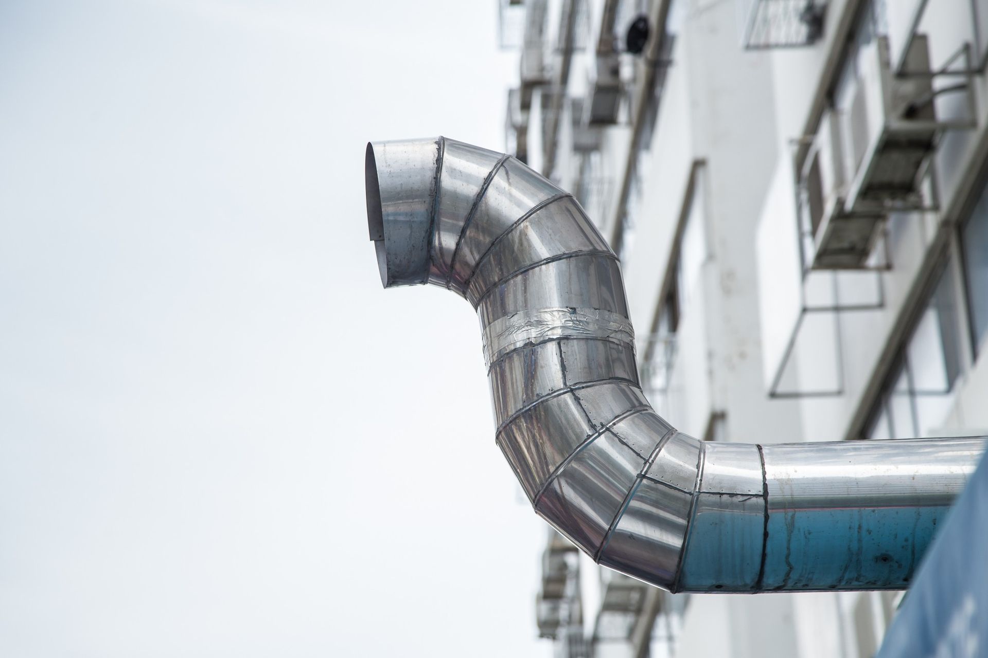 A metal pipe is attached to the side of a building.