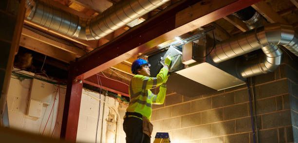 A man is working on a ventilation system in a building.