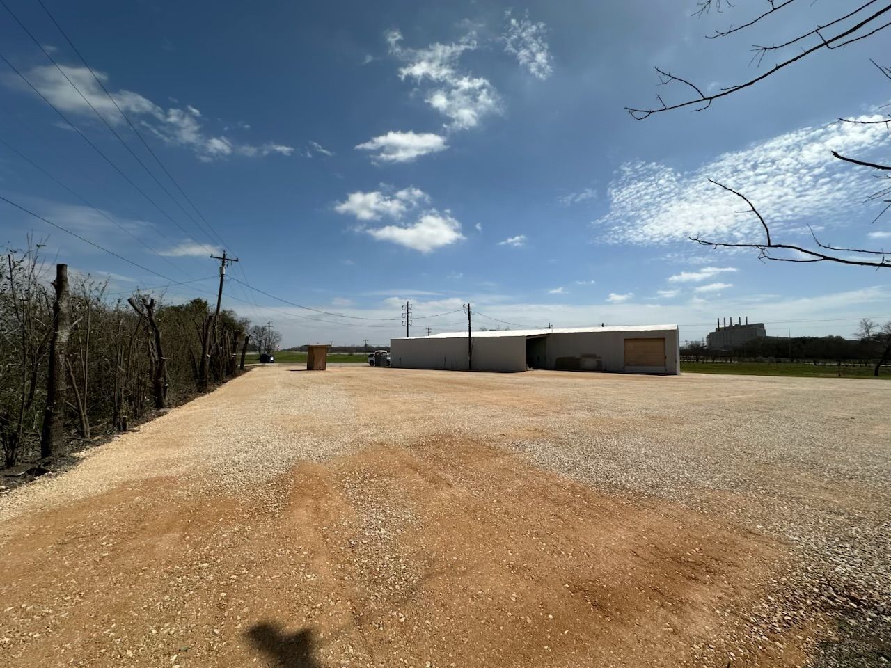 A dirt road leading to a building with a blue sky in the background.