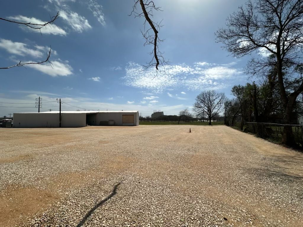 A gravel driveway with a building in the background.