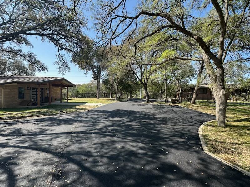 A driveway leading to a house with trees on both sides.