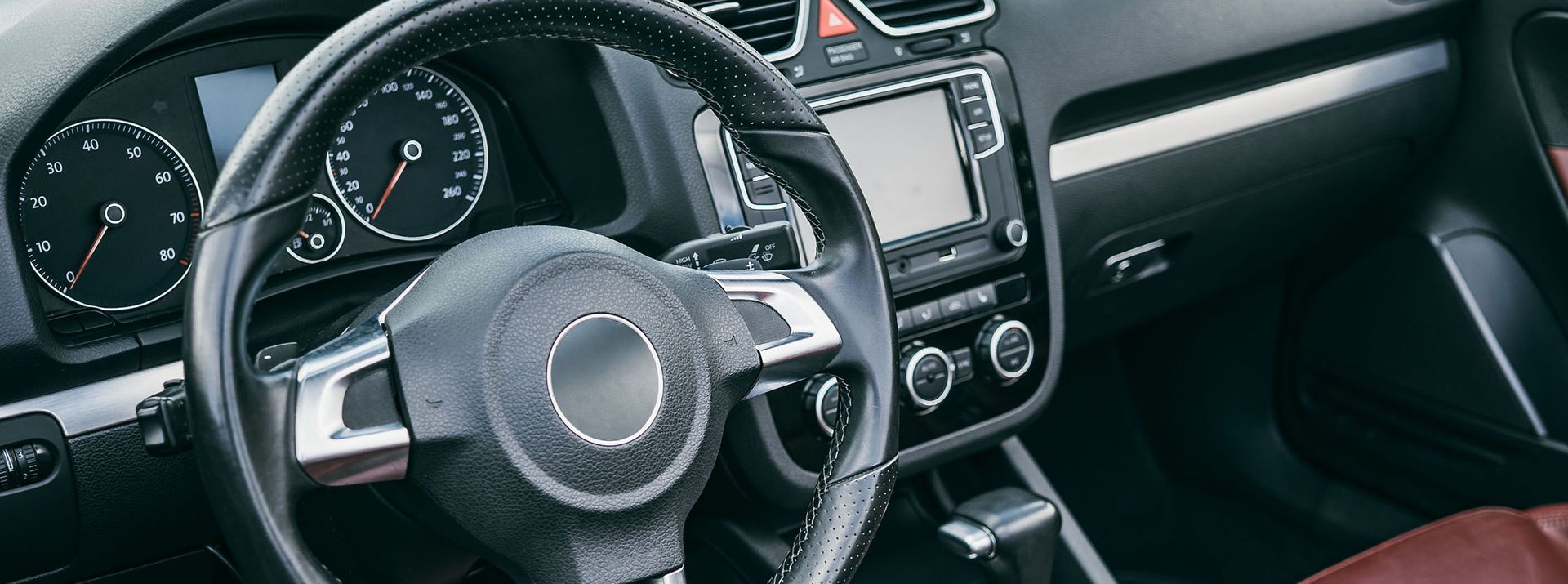 Interior view of a car, including the steering wheel, dashboard with gauges and infotainment screen.