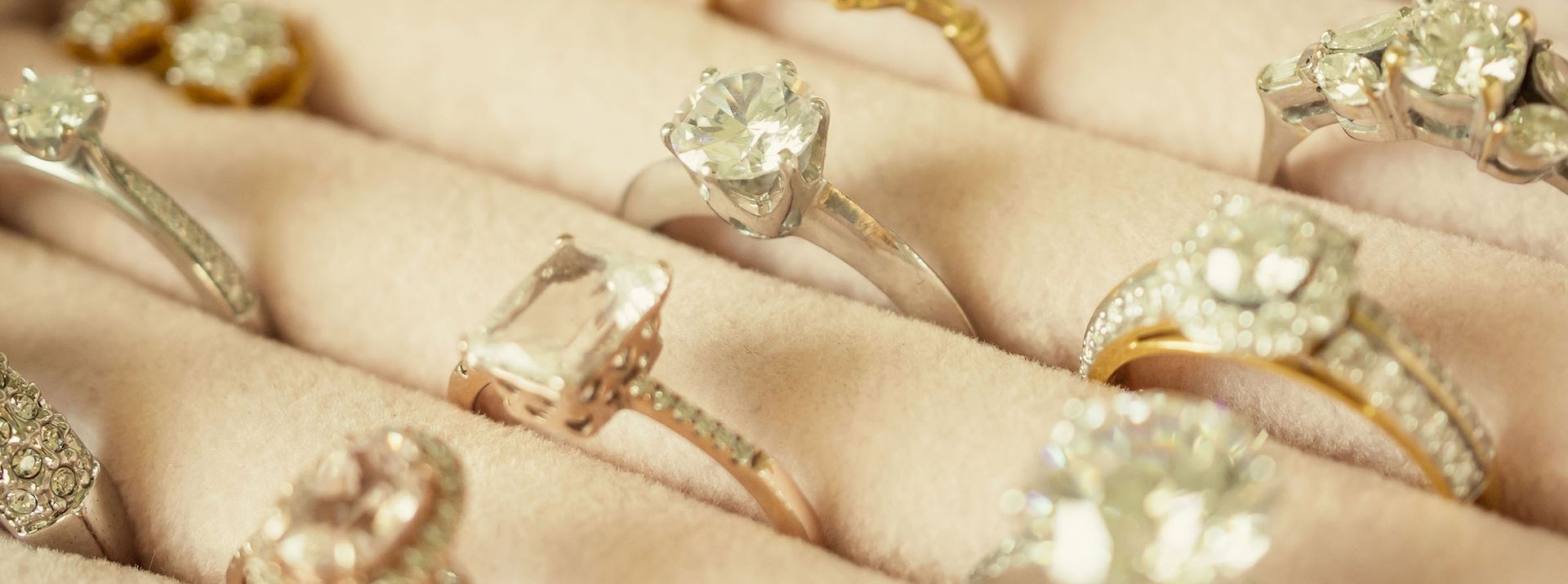 Close-up of several diamond rings on a soft, light-colored surface.