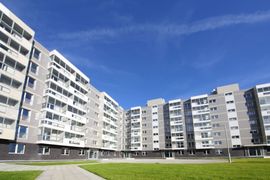 Multi-story gray apartment building with balconies, under a blue sky.