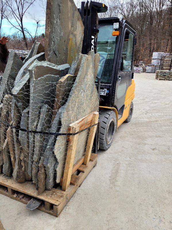 A forklift is carrying a pallet of rocks.
