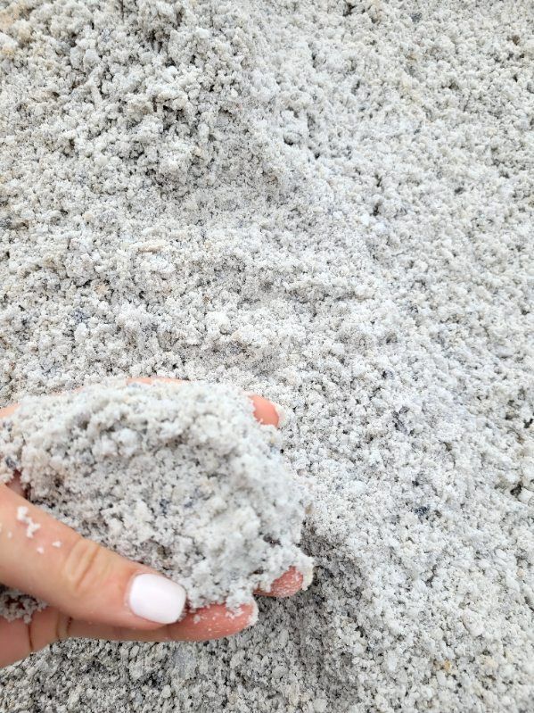 A person is holding a pile of white sand in their hand.