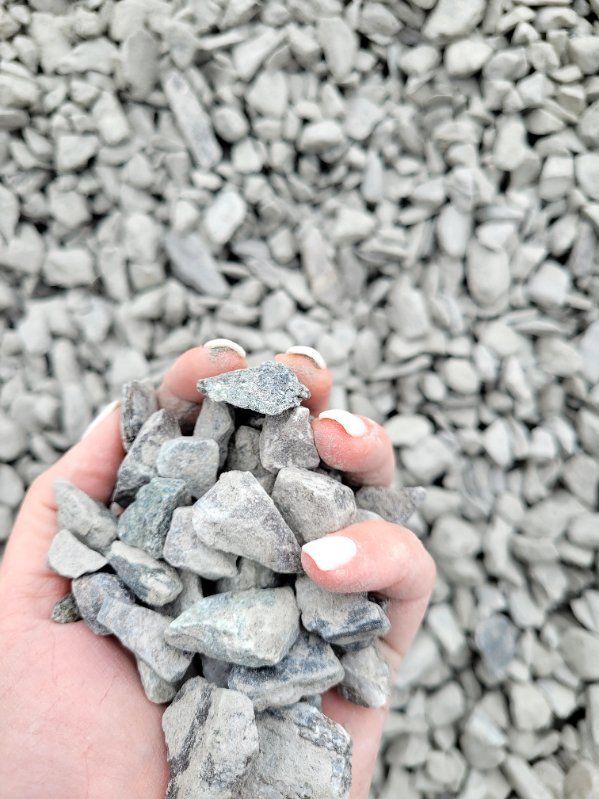 A person is holding a pile of gravel in their hands.
