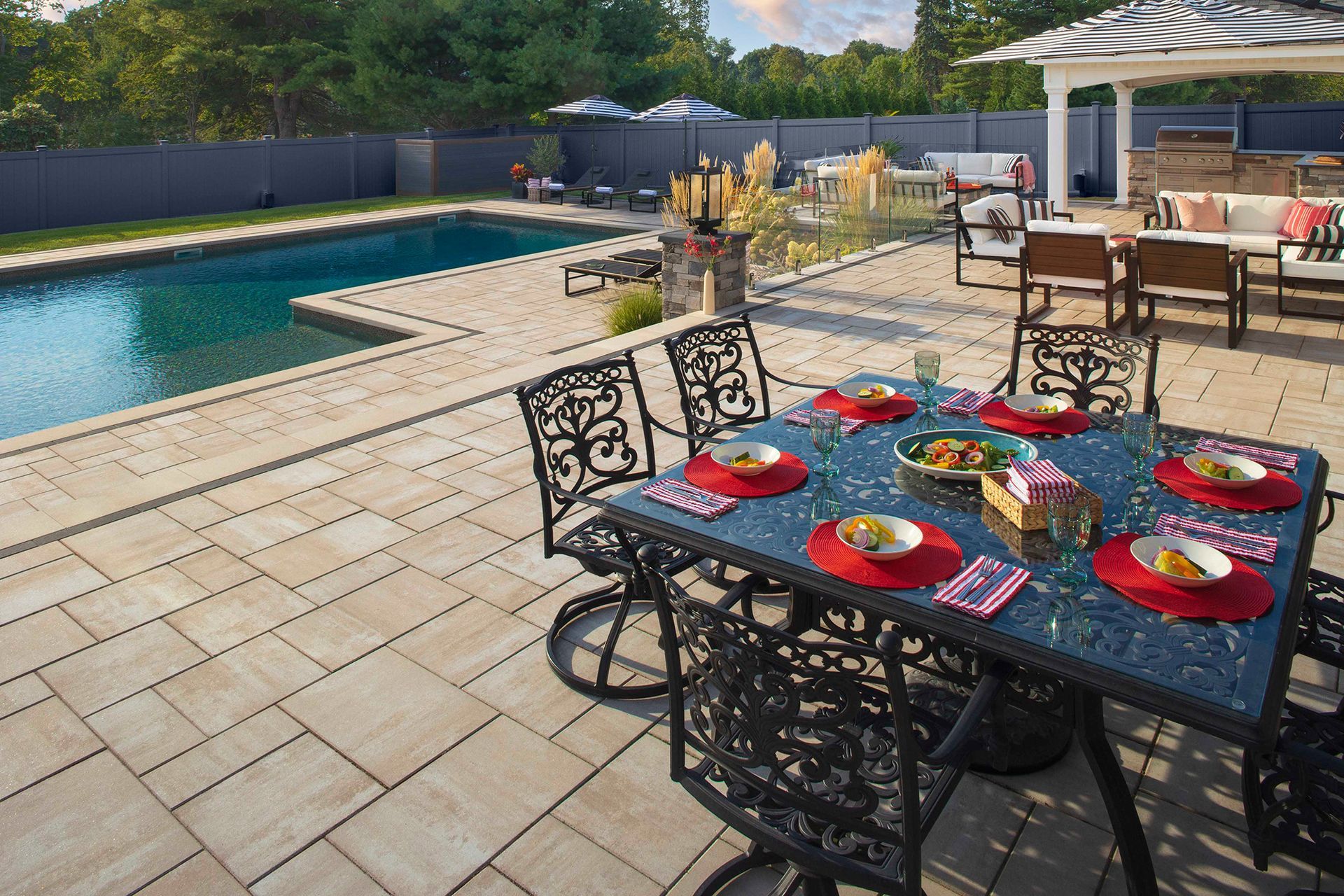 A patio with a table and chairs and a pool in the background.