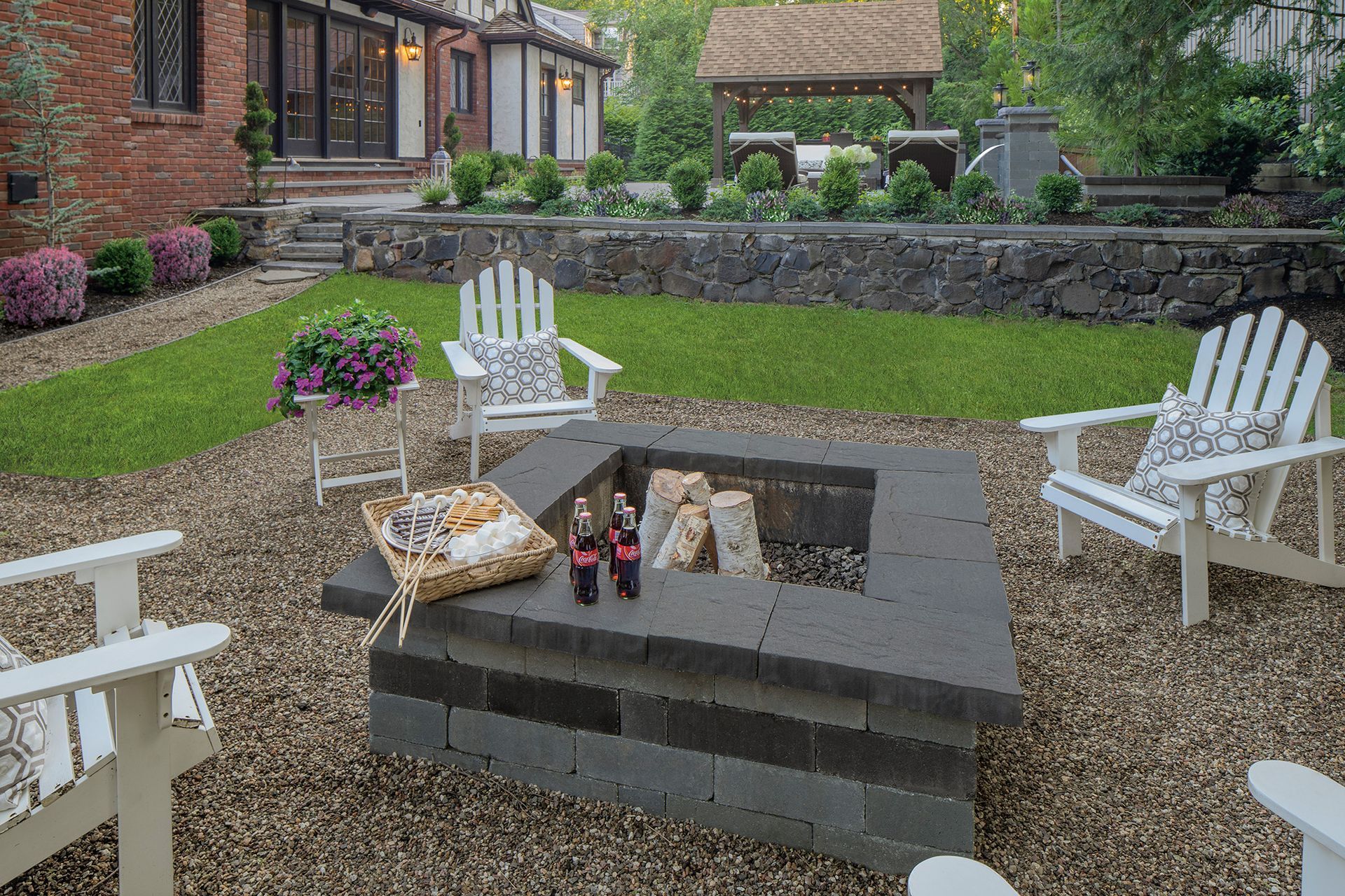 There is a fire pit in the middle of the backyard surrounded by chairs.
