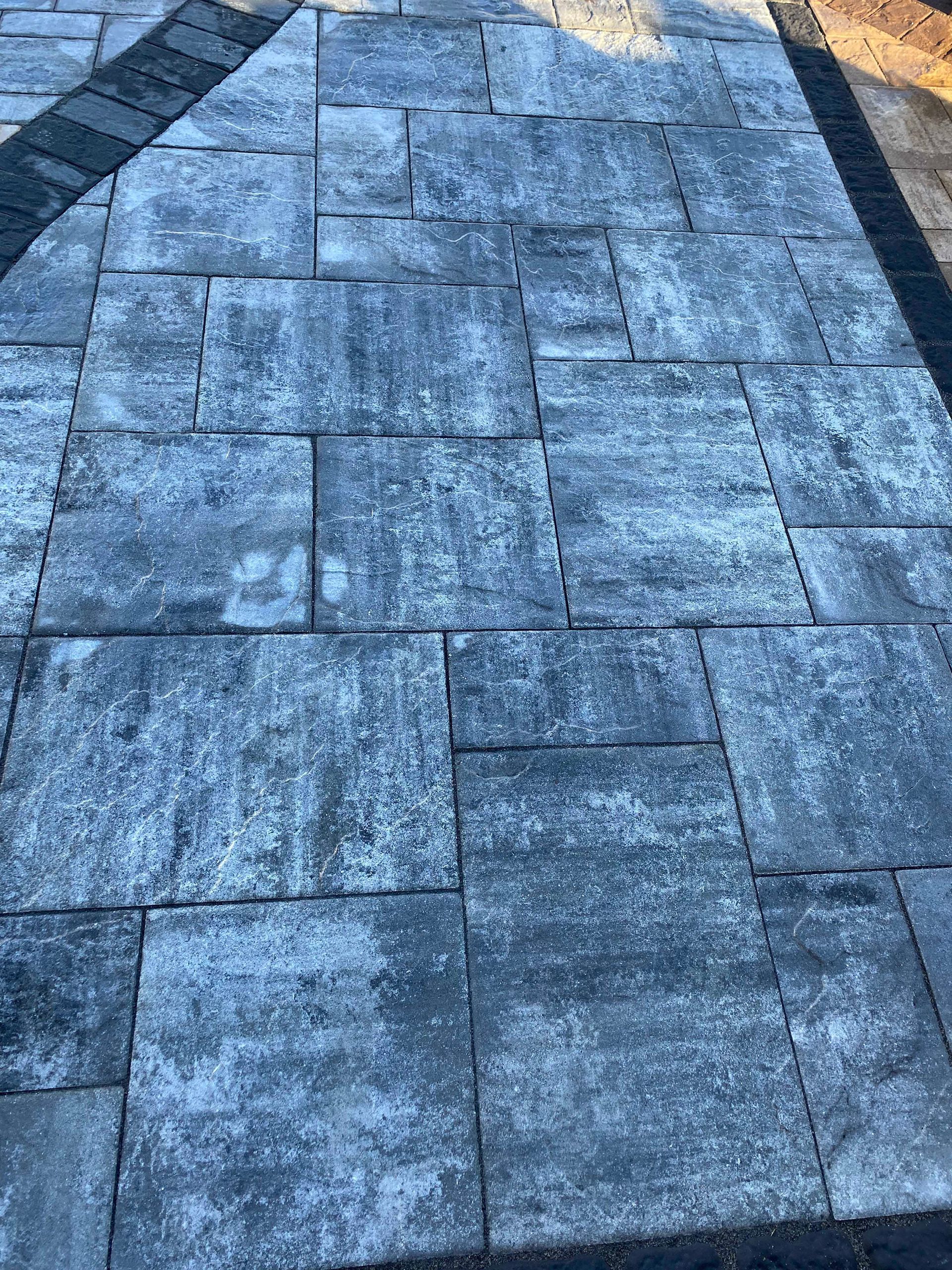 A close up of a brick walkway with a black border.