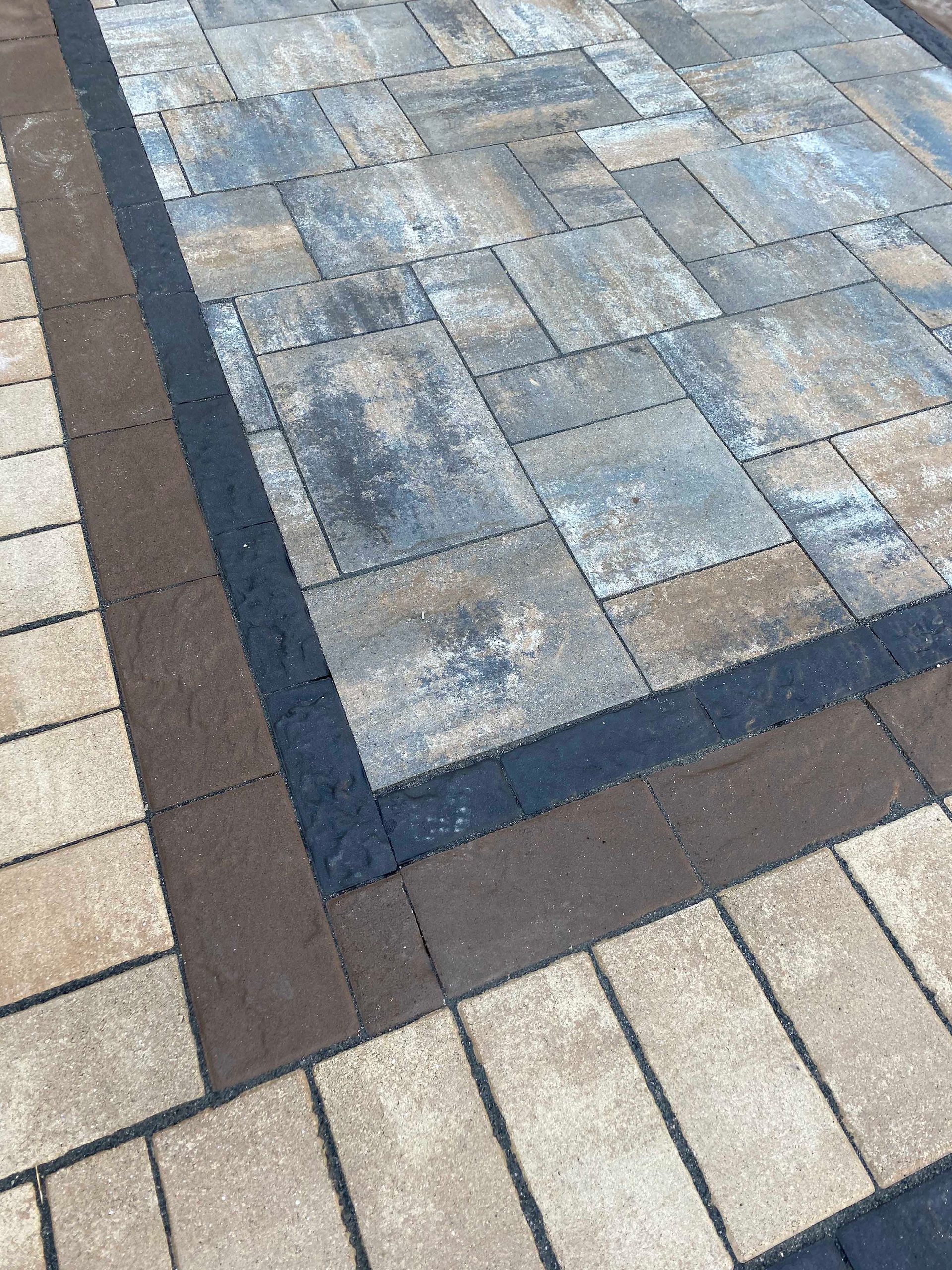 A close up of a brick walkway with a black border.