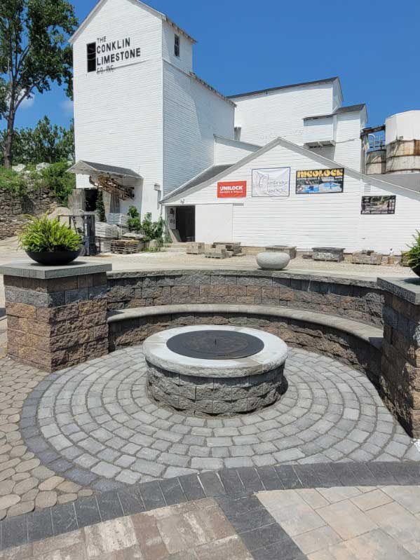 A fire pit is surrounded by bricks in front of a building.