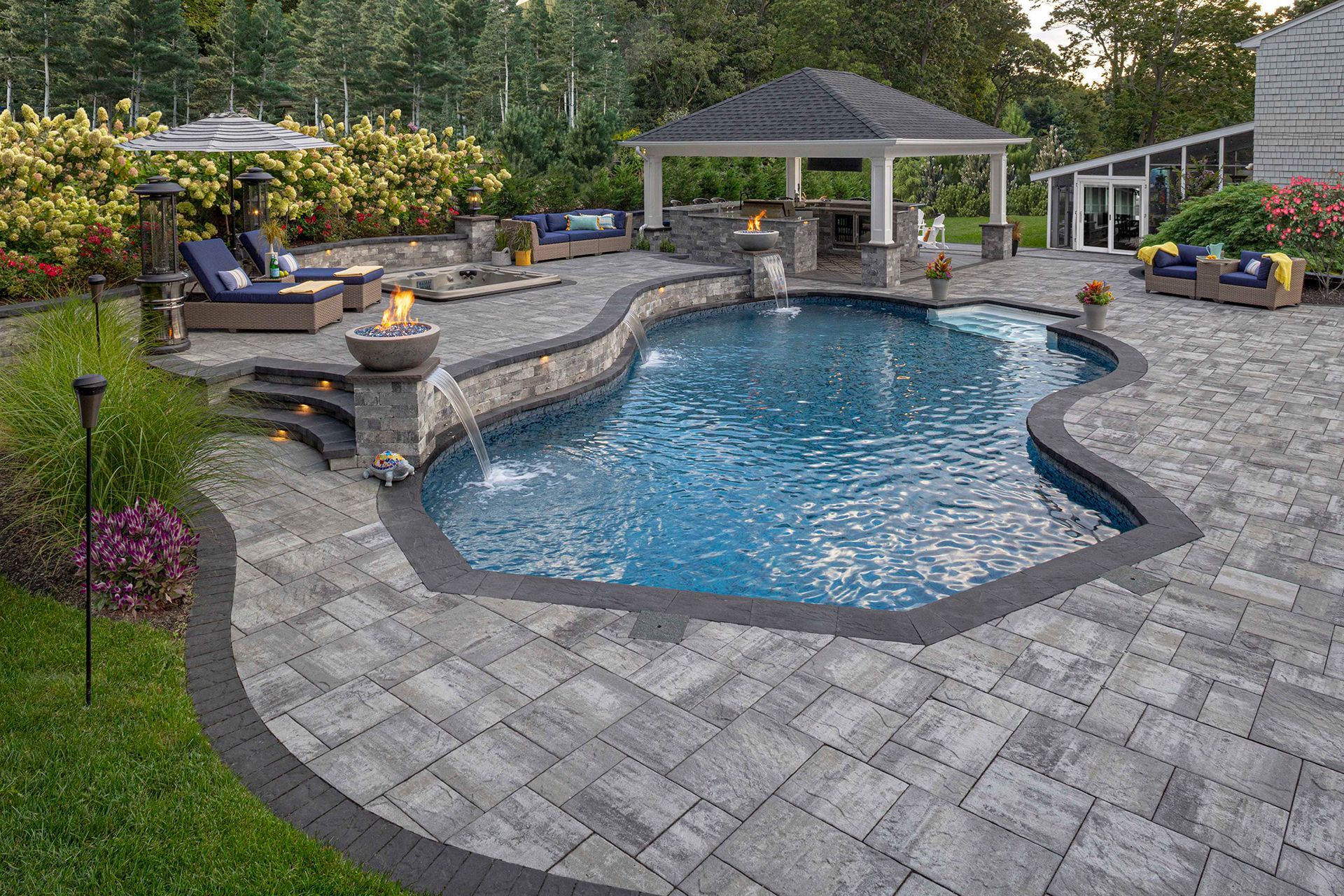 A large swimming pool is surrounded by a patio and a gazebo.